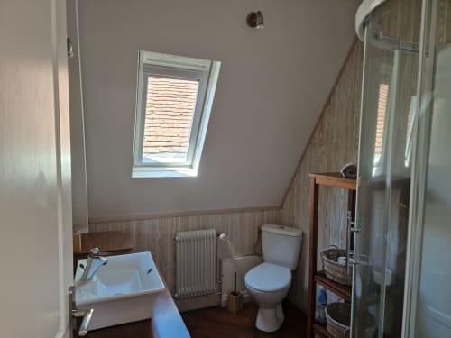 Salle de bain étage avec douche et toilettes.