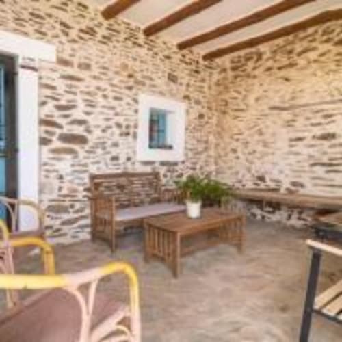 Terraza con muros de piedra rústica, muebles de madera y plantas en macetas en la villa Cortijo La Suerte en Adra, España