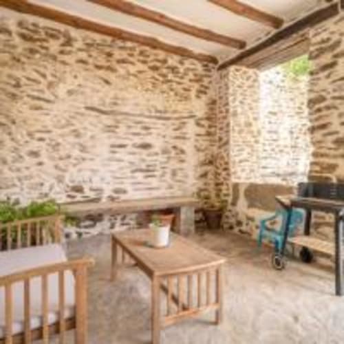 Interior rústico de villa de piedra en Paraje la Suerte, Adra, con vigas expuestas, muebles de madera y vistas al jardín