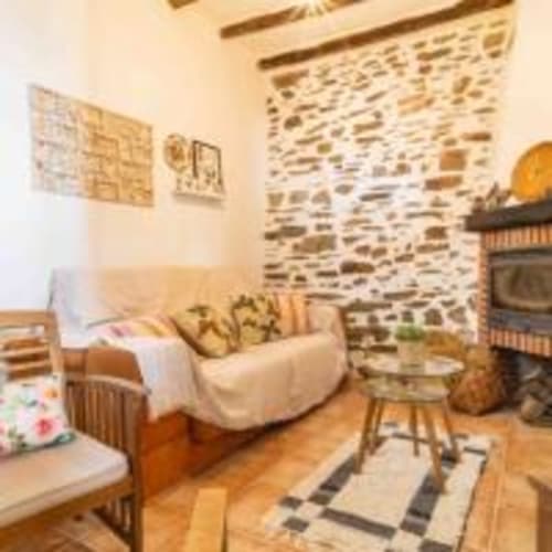 Acogedor salón de la villa Cortijo La Suerte en Adra con chimenea de piedra, muebles de madera y vistas al mar