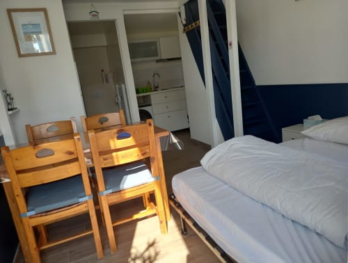 Chambre lumineuse avec chaises en bois, lit double et kitchenette aux Relais-Orbigny, L'Aiguillon-la-Presqu'île