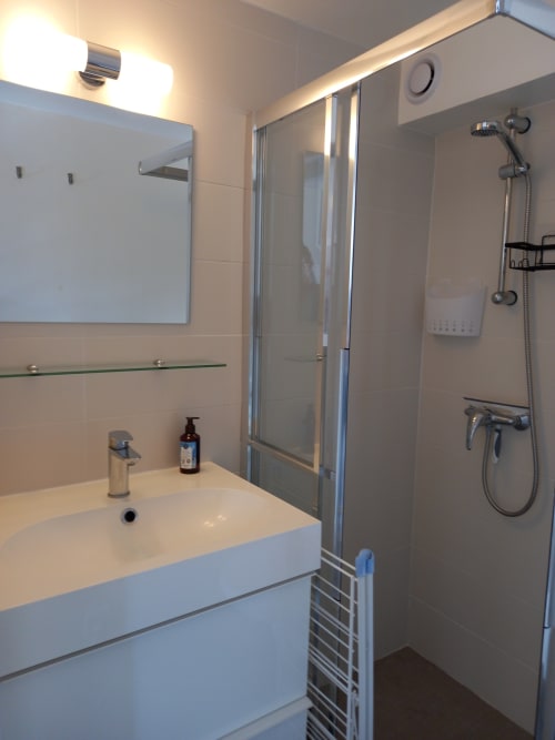 Salle de bains moderne aux Relais-Orbigny avec lavabo, miroir et douche à l'italienne avec pommeau extractible