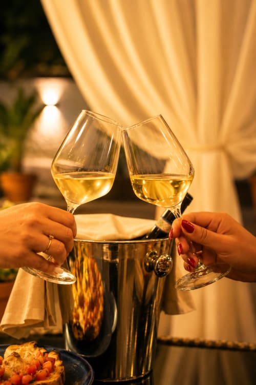 Due calici di vino bianco che tintinnano a Villa Bina Sea Hotel a Serrara Fontana durante una serata di celebrazione elegante.
