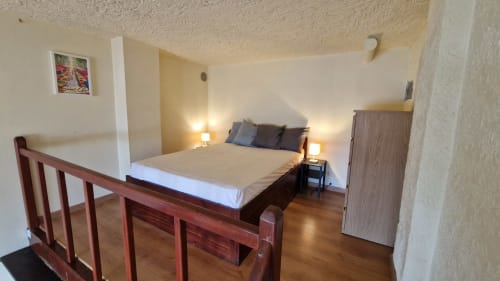 Chambre spacieuse aux Terrasses des Lecques avec vue mer, lit en bois, lampes de chevet et mobilier moderne.