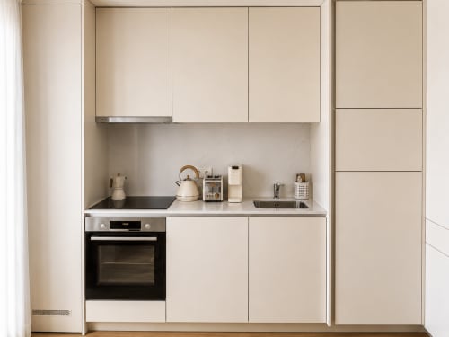 Modern minimalist kitchen in Terra Clara Garden Studio, Esposende with cream cabinets, black oven, and stainless steel