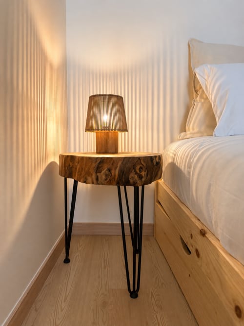 Ambiente aconchegante à cabeceira na Terra Clara Studio com criado-mudo em madeira, luminária listrada e roupa de cama branca em Esposende