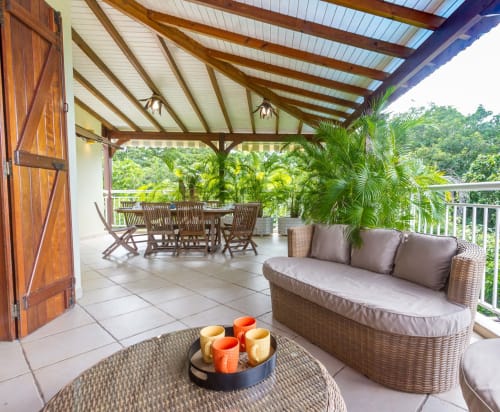 Vaste terrasse couverte , naturellement ventilée avec mobilier en rotin et teck,  espace repas et coin salon.