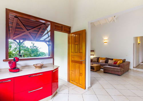 Cuisine équipée moderne avec meubles rouges, vue sur le salon et la terrasse de l'étage.