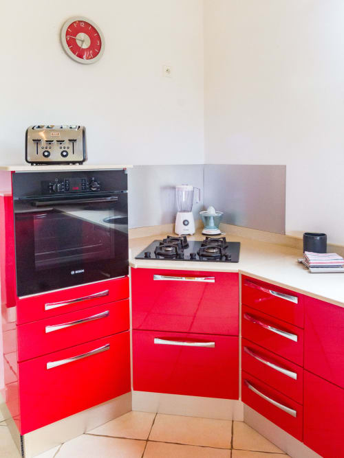Cuisine moderne rouge avec plaque de cuisson à gaz, blender et presse agrumes .
