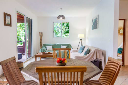 Espace de vie au rez de chaussée avec coin salon et canapé, et kitchinette donnant sur la terrasse en bois de la piscine.