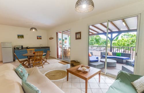 Espace de vie au rez de chaussée avec coin salon et canapé, et kitchinette donnant sur la terrasse en bois de la piscine.