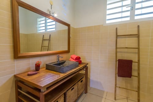Salle de bain de la chambre parentale avec vasque en pierre, meuble en teck, douche et WC.
