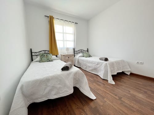 Dormitorio doble con camas blancas y almohadas decorativas en la villa Casa Laferre en La Oliva, Fuerteventura
