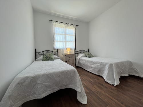 Dormitorio doble en villa Casa Laferre de La Oliva con ropa de cama blanca y cabeceros ornamentales