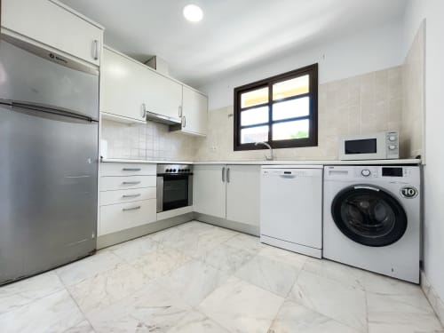 Cocina moderna con electrodomésticos de acero inoxidable, mobiliario blanco y pisos de mármol en Villa Casa Laferre, La Oliva
