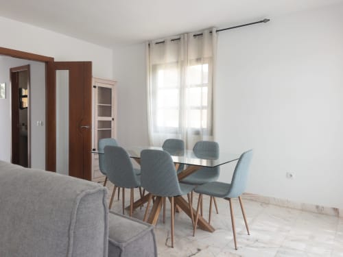 Zona de comedor moderna en villa Casa Laferre de FTV Holidays Homes, La Oliva con mesa de cristal, sillas azules y luz natural