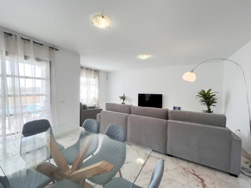 Salón moderno de la villa Casa Laferre en La Oliva con sofá gris, smart TV y lámpara de arco