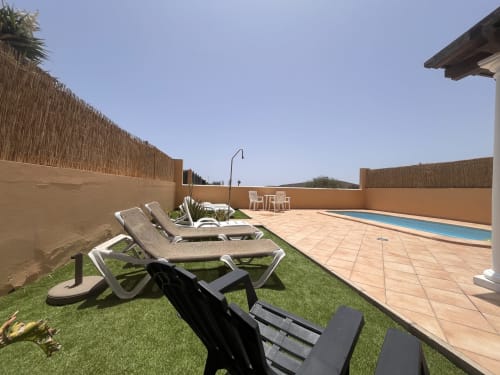 Terraza de lujo de la villa en FTV Holidays Homes, La Oliva, con tumbonas, piscina y patio cerrado bajo cielo despejado