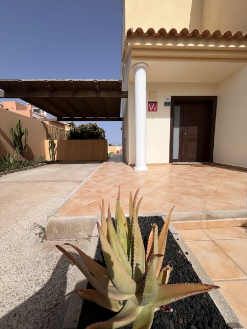 Patio de la villa Casa Laferre en La Oliva con suelo de terracota, columna blanca, plantas suculentas y pérgola cubierta