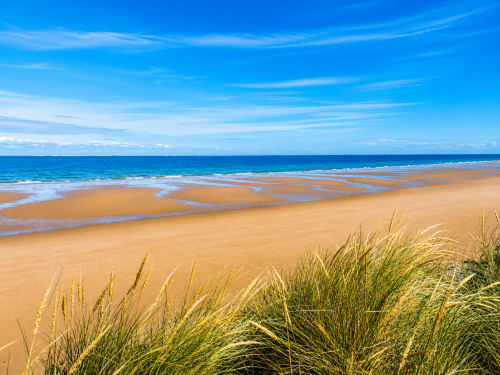 Zandstrand bij Ô de Mer, Sangatte, met gouden duinen, helmgras en blauwe oceaanhorizon