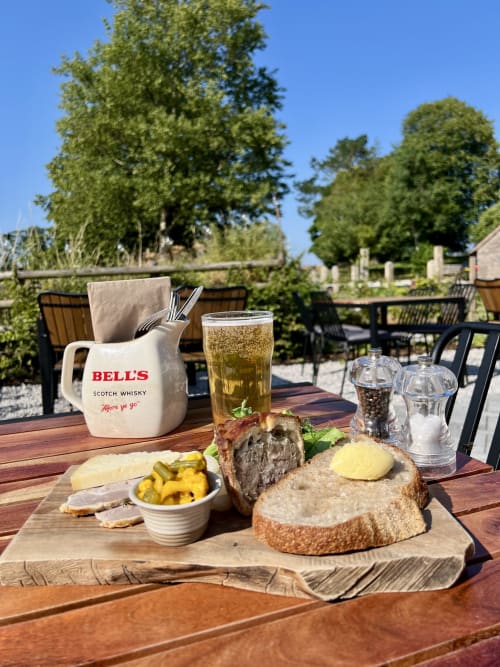Outdoor dining at Black Lion Inn, Butterton: pâté terrine, roasted vegetables, bread, and Bells whisky with beer on wooden