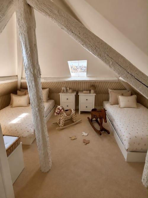 Chambre d'enfants sous combles à l'hôtel de Deauville avec lits jumeaux, poutres blanchies et décor côtier traditionnel