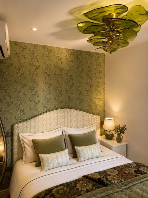 Chambre élégante de l'hôtel DEAUV HILLS à Deauville avec papier peint fleuri vert, lit capitonné et luminaires modernes.