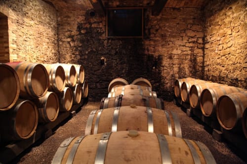 Cave à vins du Hostal Luxury Nit i Dia à Altea, Alicante avec des tonneaux en bois alignés le long de murs en pierre