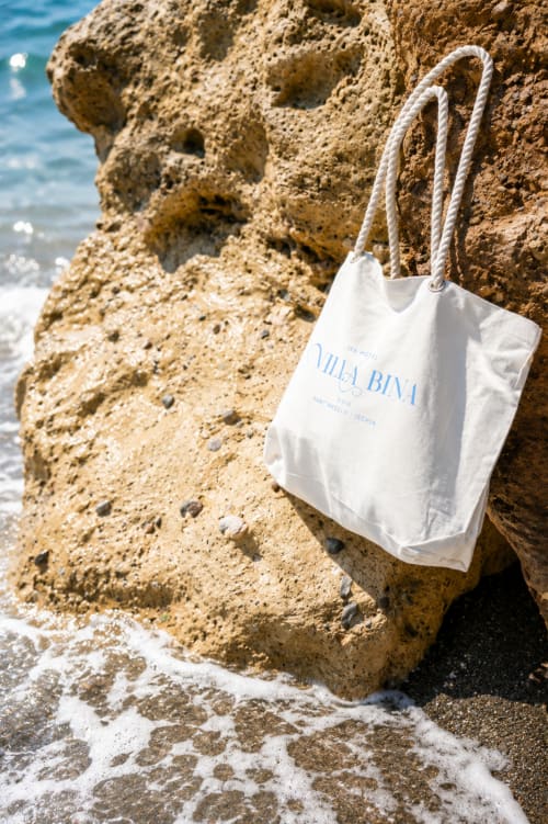 Borsa tote bianca Villa Bina Sea Hotel appesa su scogliera rocciosa a Ischia, Italia