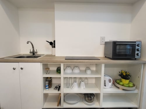 Compact kitchen in Historic Loft apartment at Cosy in Cork, featuring sink, toaster oven, open shelving with dishes and