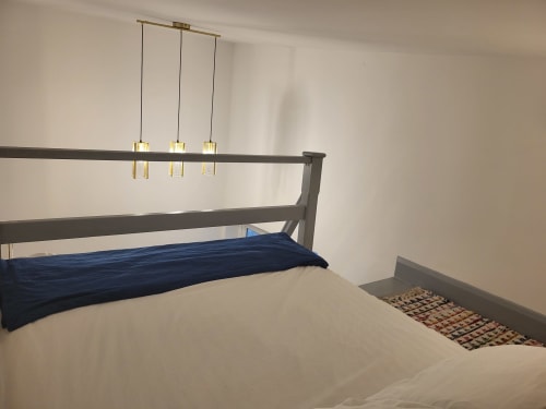 Modern bedroom in Cork loft with dark wood bed frame, blue bedding, pendant lights, and minimalist beige walls