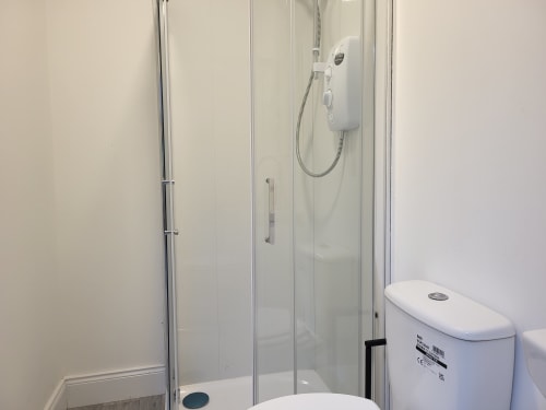 Modern bathroom in Cosy Studio Cork with glass shower enclosure, white toilet, and wall-mounted showerhead