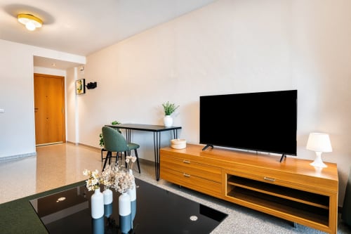 Salon moderne avec TV écran plat, mobilier en bois et décoration lumineuse près de la plage de Valence