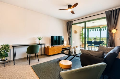 Salon moderne avec vue mer sur balcon, télévision, assises confortables et bureau près de la plage de Valence