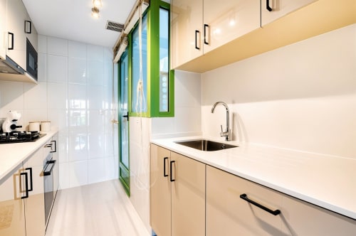 Cuisine moderne avec armoires blanches, cadre de fenêtre vert et évier en acier inoxydable dans un appartement en bord de mer à Valence
