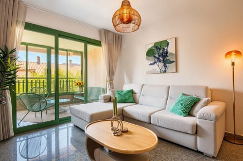 Séjour moderne d'appartement à Valence avec balcon vue mer, canapé beige, table en bois et accès terrasse verdoyante.