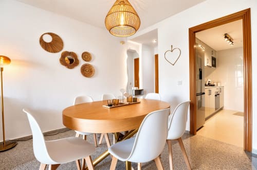 Salle à manger contemporaine avec table en bois, chaises blanches, décoration murale tissée et cuisine ouverte dans un appartement à la plage de Valence