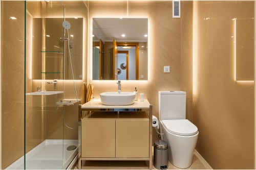 Salle de bain moderne beige avec miroirs illuminés, vasque blanche, douche et toilettes dans un appartement à Valencia Beach