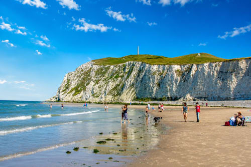 Beachgoers enjoy Sangatte beach with iconic white cliffs and turquoise waters near Ô de Mer hotel