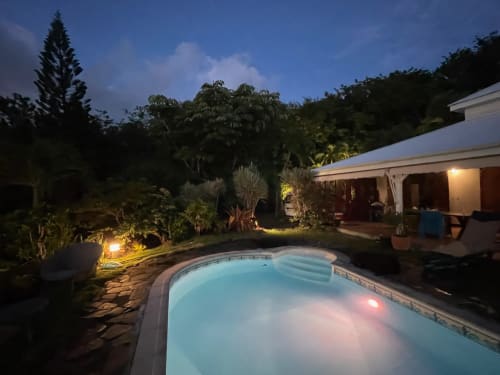 Vue de la piscine et de la maison en soirée avec son jardin illuminé