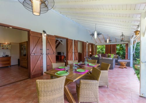 Terrasse de la Villa avec table à manger, chaises en rotin, et grand salon de jardin pour profiter du jardin et de la piscine.