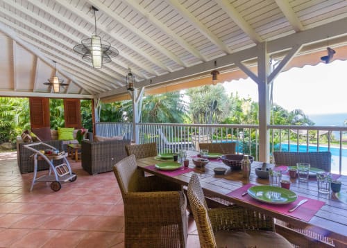 Terrasse de la Villa avec table à manger, chaises en rotin, et grand salon de jardin pour profiter du jardin et de la piscine.