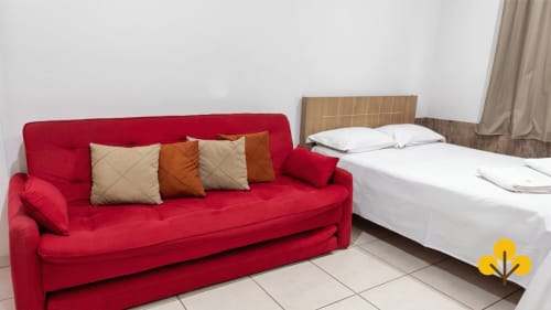 Studio no Wellington Rodovalho com sofá-cama vermelho e cama de casal, quarto de hotel em Goiânia