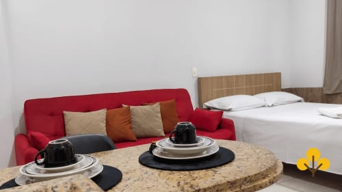 Kitnet em Wellington Rodovalho Goiânia com sofá vermelho, mesa redonda e cama