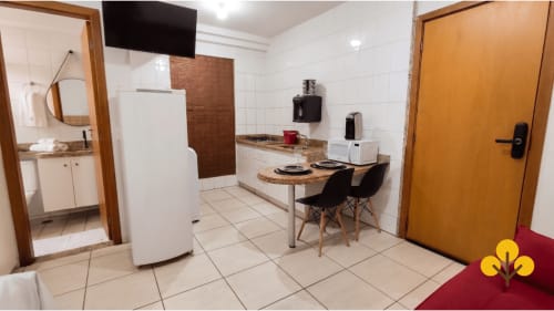 Cozinha e área de refeições do flat no hotel de Goiânia com fogão, geladeira, mesa de jantar e amenidades modernas