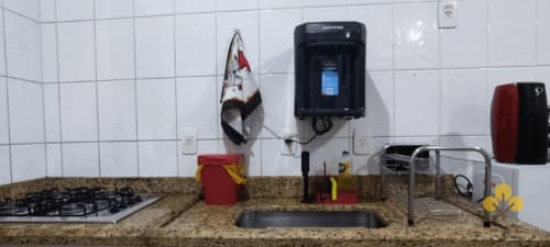 Bancada da cozinha do estúdio Wellington Rodovalho em Goiânia com fogão a gás, pia, purificador de água e ferro ligado