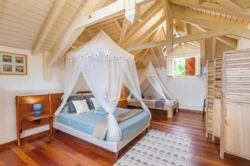 Chambre Villa Jasmine avec lit à baldaquin, poutres apparentes et ambiance tropicale aux Villas Amboise Guadeloupe