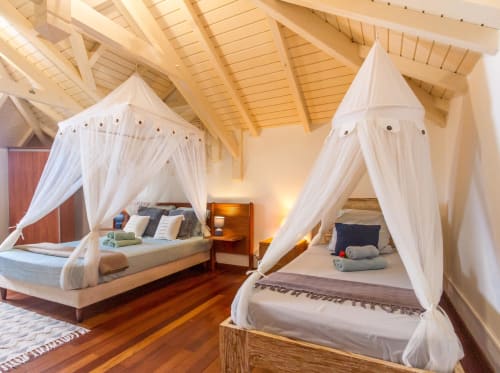 Luxueuse chambre de villa avec deux lits à baldaquin, poutres apparentes et vue sur mer à Deshaies, Guadeloupe