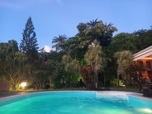 Vue de la piscine et de la maison en soirée avec son jardin illuminé