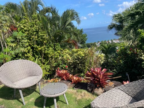 Jardin tropical avec salon en rotin surplombant la mer des Caraïbes .